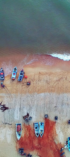 Aerial view of boats on a sandy beach with fishing nets