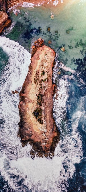 Aerial view of a rocky island with waves crashing