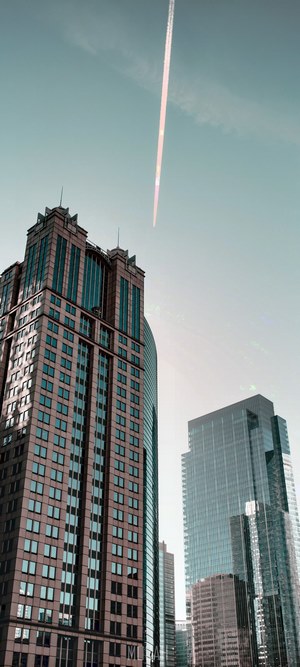 Airplane contrail over skyscrapers