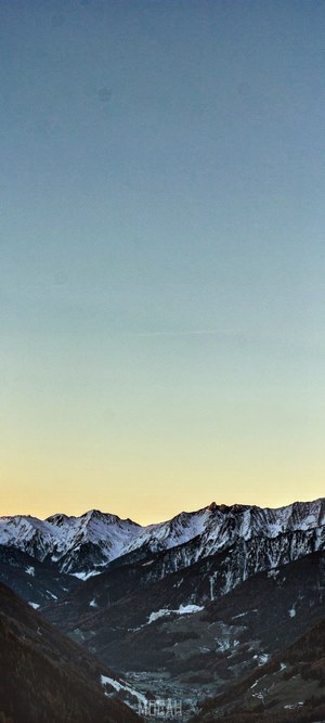 Snow-capped mountains over a valley at dusk
