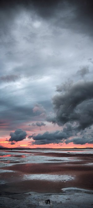 Dramatic sunset over a salt flat with dark clouds