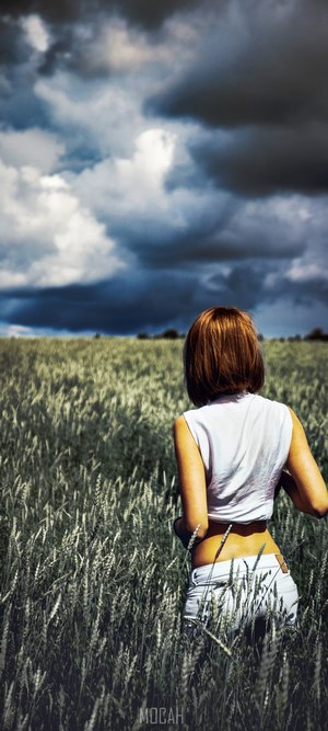 Woman in a wheat field under stormy clouds