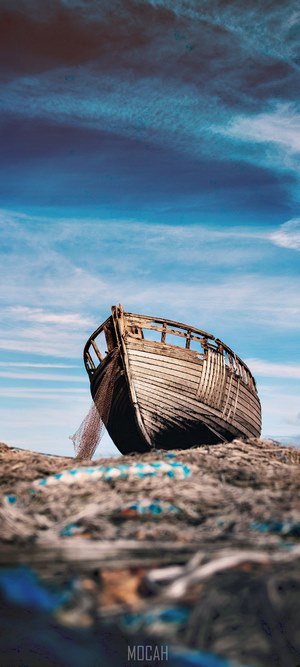 Abandoned wooden boat on a beach with fishing nets