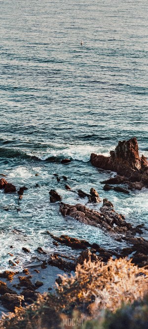 Ocean waves crashing on rocky shore with a buoy