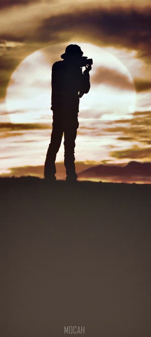 Silhouette of a man with a camera against a sunset