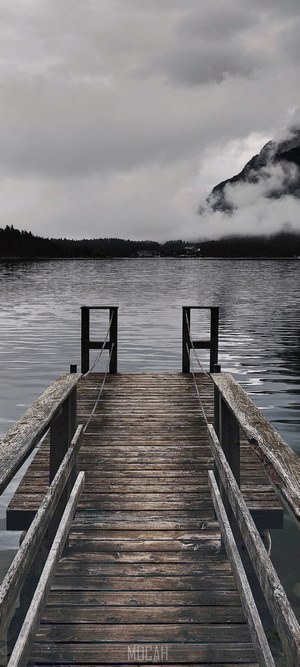 Wooden pier on a lake with misty mountains