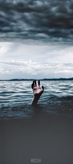 Hand reaching out of dark water under stormy sky