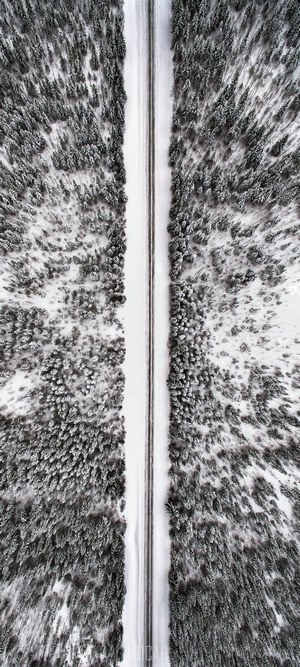 Aerial view of a road through a snowy forest in Jamtland County