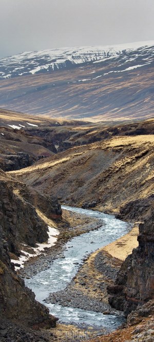 River flowing through a rocky valley with snow-capped mountains