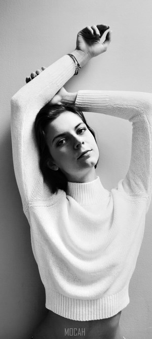 Woman in white sweater with arms raised