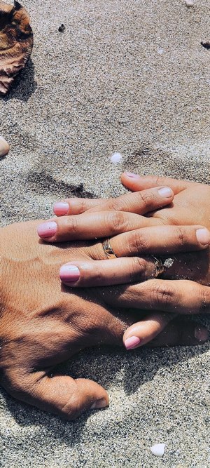 Couple's hands with wedding rings on sand