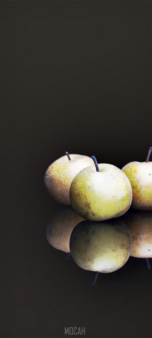 Three pears on a dark reflective surface