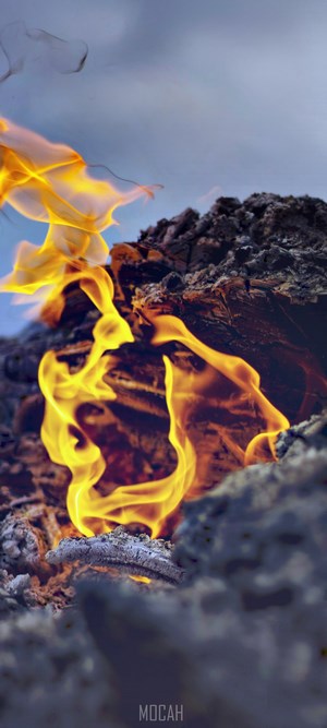Fire burning on ash with smoke against sky