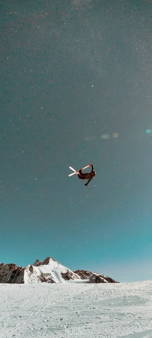 Skier performing a trick in the sky over snowy mountains