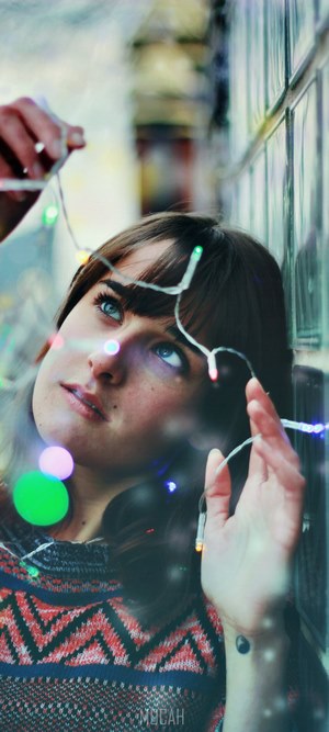 Woman with Christmas lights near a tiled wall
