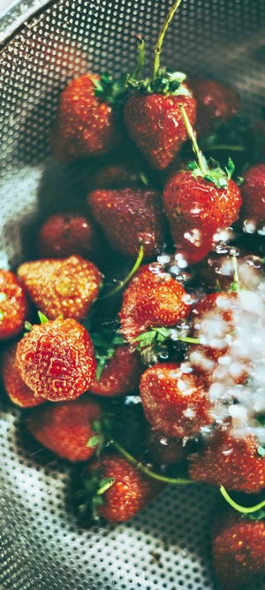 Strawberries being washed in a colander