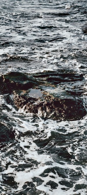 Waves crashing on dark rocks