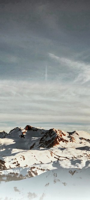 Snowy mountain peaks with a jet plane contrail