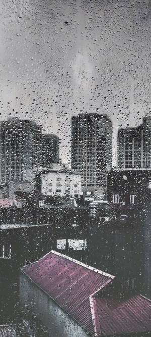 Rainy city view through a window with skyscrapers and rooftops