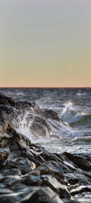 Waves crashing on rocks at sunset