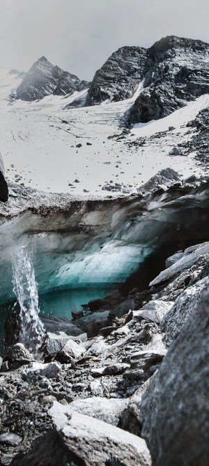 Glacial cave with waterfall and mountains