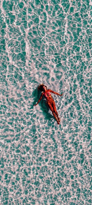 Woman in bikini floating on back in clear ocean water