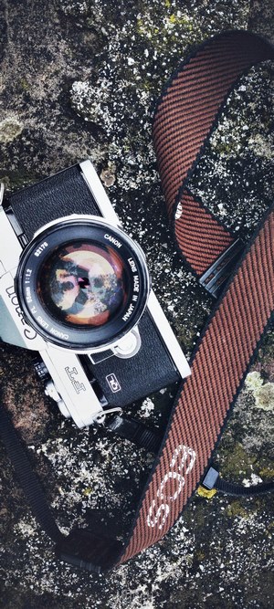 Canon vintage camera with EOS strap on stone