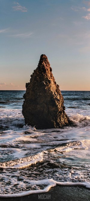 Jagged rock formation in the ocean with waves