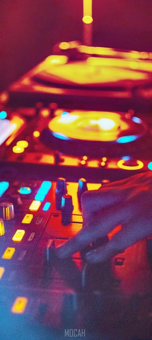 DJ mixing music on a console with colorful lights