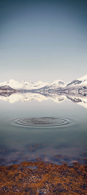 Snow-capped mountains reflected in a calm lake with ripples