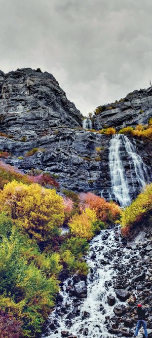 Waterfall cascading down rocky mountain with autumn foliage