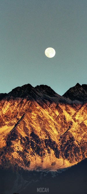 Moon over sunlit mountains
