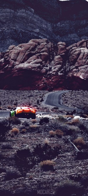 Sports car driving on a winding road in a rocky desert landscape