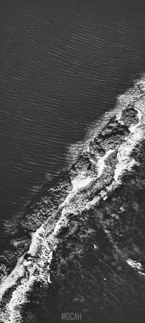 Aerial view of ocean waves crashing on a rocky shore