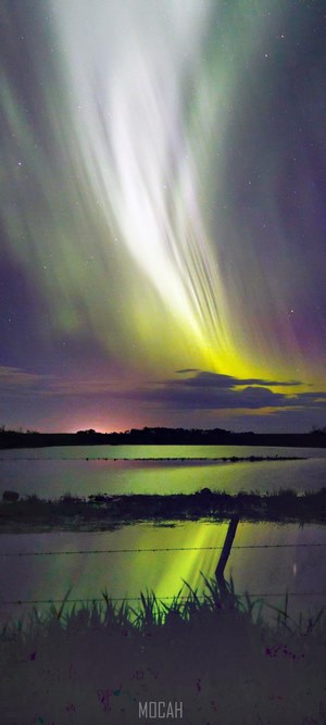 Aurora Borealis over water with fence