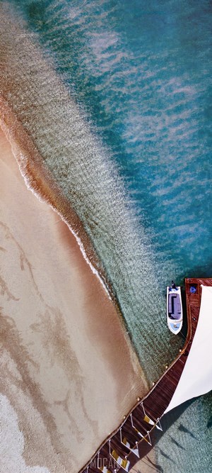 Aerial view of a beach with a pier and a boat
