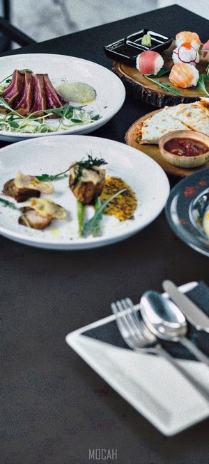 Gourmet dishes and sushi on a dark table