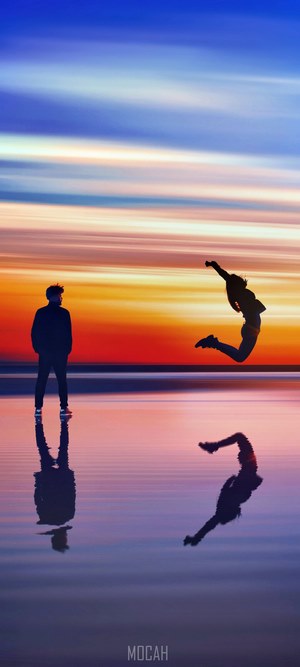 Two people silhouetted against a colorful sunset sky