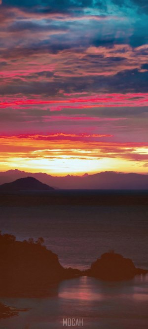 Sunset over the ocean with mountains and islands