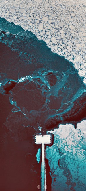 Aerial view of a pier extending into icy ocean water