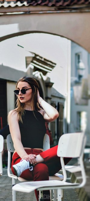 Woman in red pants and sunglasses sitting on cafe chairs