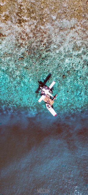 Seaplane floating on turquoise water near coral reef