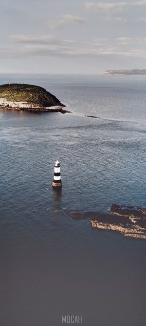 Black and white lighthouse in the sea near an island