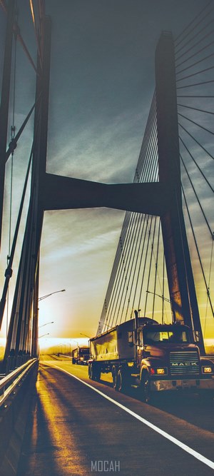 Mack trucks on a bridge at sunrise