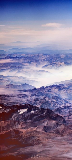 Rugged mountain ridges covered in blue clouds and fog