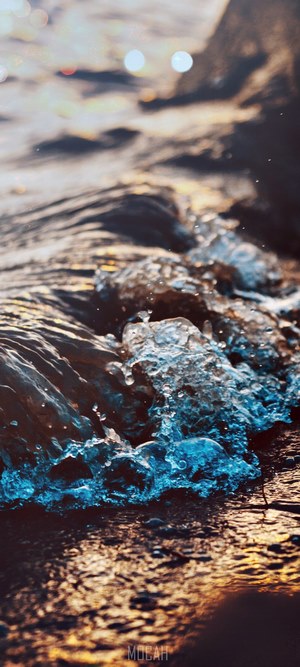 Close-up of ocean waves with orange light reflection