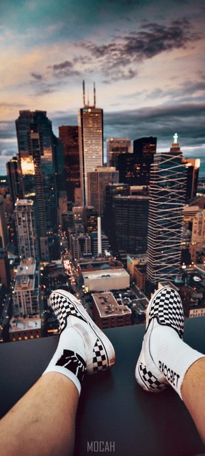 Person sitting on a rooftop overlooking a city at dusk