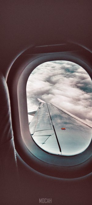 Airplane wing over clouds seen through window