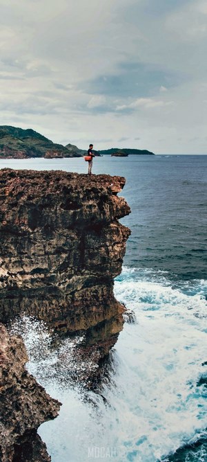 Person standing on a rocky cliff overlooking the sea