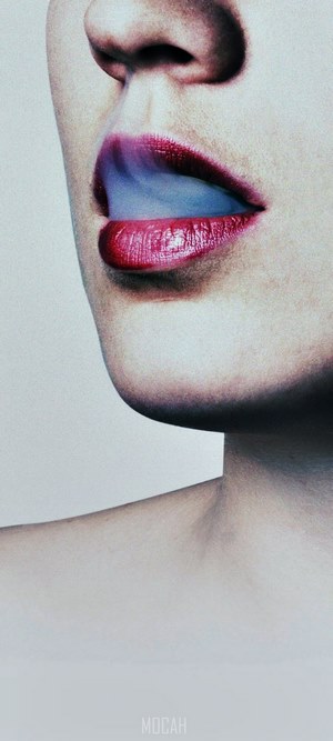 Woman exhaling smoke from red lips